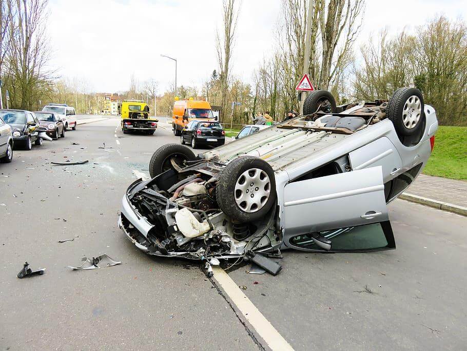 Upside-down destroyed silver car on the street after an accident involving a defective automobile