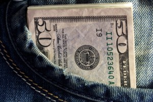 a 50 dollar bill and more cash inside a denim pocket 