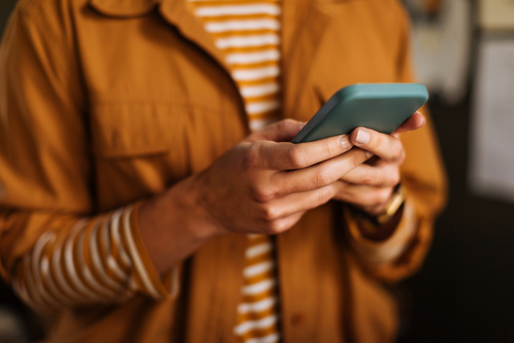 Close-up of a hand holding a smartphone, screen facing the model.